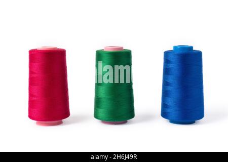 Pink, blue and green threads on a white background. Side view of colored sewing thread bobbins. Stock Photo