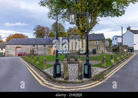 The stone celtic cross war memorial situated in the Market Place in the centre of Castleton village, Peak District, Derbyshire, England. Stock Photo