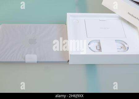 Unboxing the new Apple MacBook Pro 14 M1 Pro 2021 laptop out of the box. New laptop in apple packaging on the table at home. Online shopping concept. Stock Photo