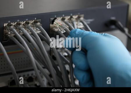 Person working in network server room with fiber optic hub for digital communications and internet Stock Photo