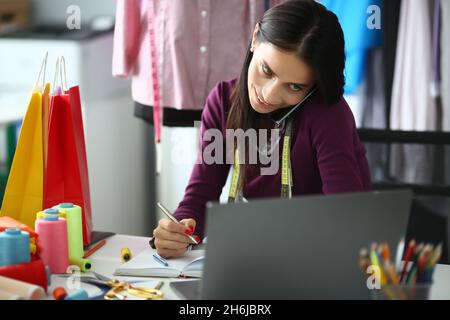 Portrait of young beautiful woman fashion designer talking on phone at workplace Stock Photo