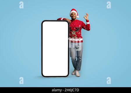 Happy black guy posing with cellphone and showing okay, mockup Stock Photo