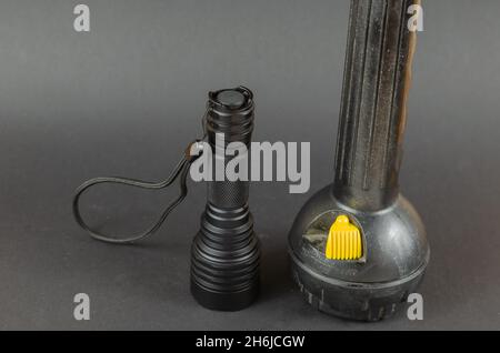 Small Modern tactical and large obsolete flashlights on gray background. Selective Focus. Stock Photo