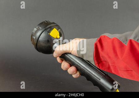 A man in workwear is holding a hand flashlight. Safety first is a concept. Selective focus. Stock Photo