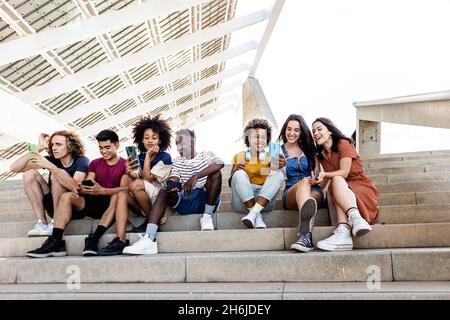 Group of diverse hipster friends students using mobile phone outdoors Stock Photo