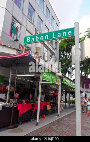 A green street name sign for Baboo Lane with the Minora Centre building in the background on Serangoon Road in Little India, Singapore. Stock Photo