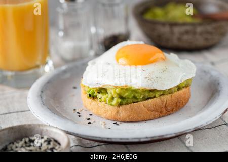 Breakfast avocado sandwich with fried egg and glass of orange juice on table, closeup view, selective focus Stock Photo