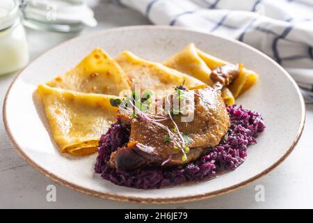 Portion of duck leg with red cabbage and potato pancakes, a traditional autumn dish in Eastern Europe. Stock Photo