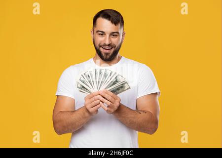 Excited happy middle aged european man rejoices to victory and looks at a lot of money in hands Stock Photo