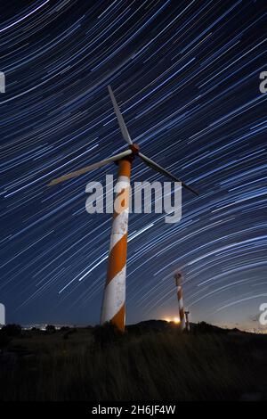 Wind turbine and Star trails in the background Stock Photo