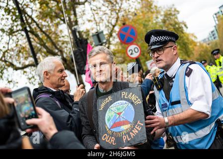 Police engaging with a protestor refusing to move from the road, Rise and Rebel march, Extinction Rebellion, London, UK. 13th November 2021 Stock Photo