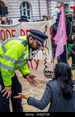 Police engaging with a protestor refusing to move from the road, Rise and Rebel march, Extinction Rebellion, London, UK. 13th November 2021 Stock Photo