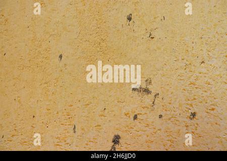 Old, yellow textured wall stained with cement spots, for background use. Stock Photo