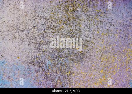 Old wall with colored layers of paintings (yellow, blue, pink and gray), textured background. Stock Photo