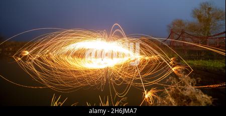 Steel wool sparks reflecting water Long exposure night landscape. Stock Photo