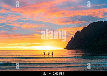 Cheerful woman with friends having fun in the sea during the midnight sun, Ersfjord, Senja, Troms county, Norway, Scandinavia, Europe Stock Photo