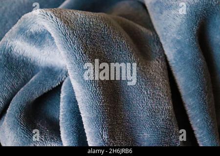 Close-up of blue, gray, soft, warm, comfortable blanket, iluminated by early morning light, just after waking up. Stock Photo