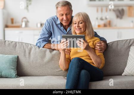 Happy Senior Couple Using Digital Tablet Browsing Internet At Home Stock Photo