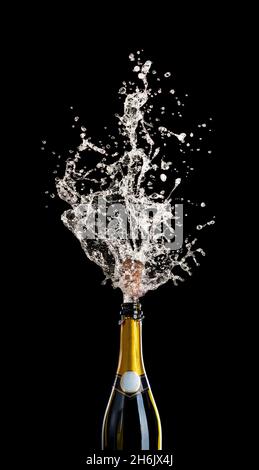 champagne bottle with cork flying with splashing liquid on black. concept of celebration, party. Stock Photo