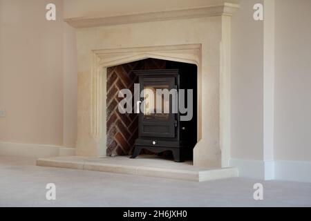 Clavering, England -  April 6 2020: New Home cast iron wood burning stove with stone surround, mantelpiece and hearth Stock Photo