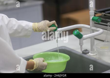 Closeup of the hand of woman scientist taking water to take the experiment in the laboratory Stock Photo