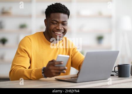 Young black man entrepreneur working on laptop and using cellphone Stock Photo