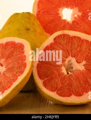 The photo shows a round piece, a pomelo slice. The inside of the exotic  fruit is pink in color, on the outside there is a yellow-green peel. Citrus  si Stock Photo 