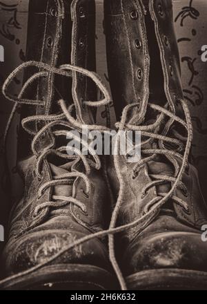 Old weathered untied high top leather boots on a shelf Stock Photo