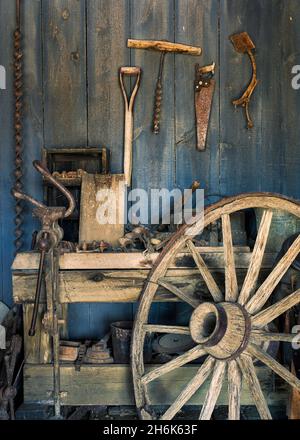 Old wooden wagon wheel against work bench in blacksmith repair shop Stock Photo