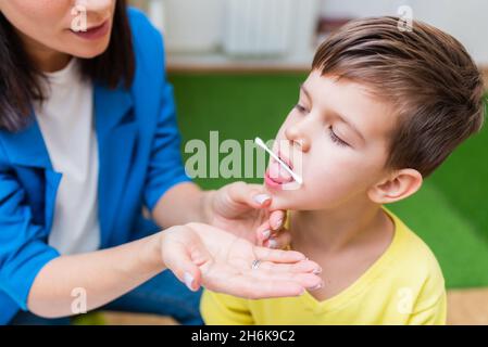 A beautiful woman speech therapist deals with the boy and teaches him the correct pronunciation and competent speech. Stock Photo