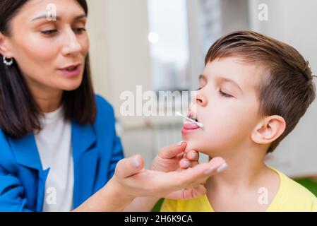 A beautiful woman speech therapist deals with the boy and teaches him the correct pronunciation and competent speech. Stock Photo