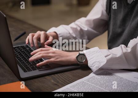 Close-up of office worker sitting at her workplace and typing document on laptop at office Stock Photo