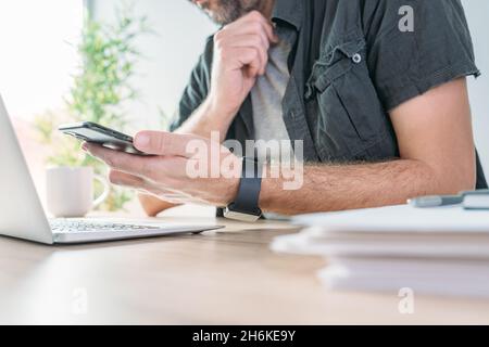 Freelancer using mobile smart phone in home office, selective focus Stock Photo