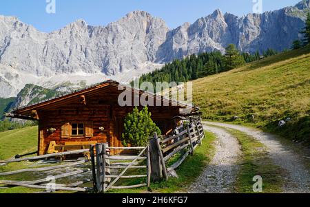 a pathway leading through the alpine scenery with log cabins in the Dachstein region in Austria (Neustatt Alm in Styria) Stock Photo