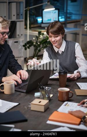 Business couple working with laptop typing documents while working at office till late night Stock Photo