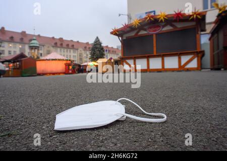 Magdeburg, Germany. 16th Nov, 2021. A lost, medical mouth-nose protection lies on the ground in front of the Christmas market stalls. Despite rising infection figures, Christmas markets in Saxony-Anhalt should be able to take place. If a distance of 1.5 meters is maintained or a mask is worn in case of non-compliance, it is possible to hold the market. The Christmas market is scheduled to open on 22 November 2021. Credit: Klaus-Dietmar Gabbert/-Zentralbild/ZB/dpa/Alamy Live News Stock Photo