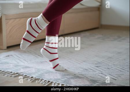 Close up photo of womans slim foot in striped warm stockings at cozy home Stock Photo