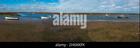 Panoramic view, of boats afloat in sunshine at Mow Creek Brancaster Staithe Harbour North Norfolk England Stock Photo