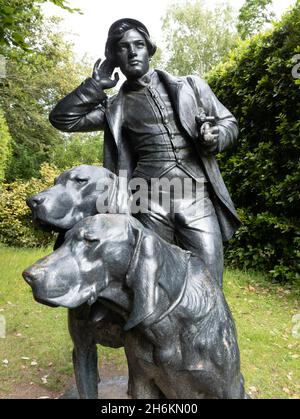 Statue of two dogs and male huntsman in the grounds at now National trust property Anglesey Abbey Lode near Cambridge England Stock Photo