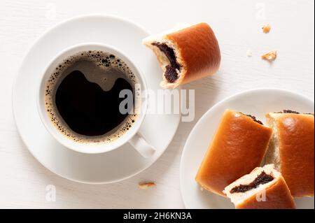 Cup of black coffee with Czech plum jam buns on white. Top view. Stock Photo