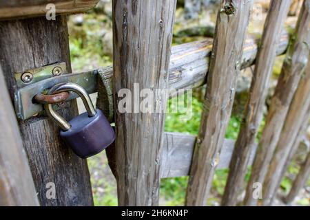 The padlock locked on a gate in a wooden fence. Stock Photo
