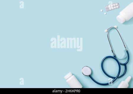 Medical concept, flat lay on blue background. Copy space. Stethoscope, pills, nasal spray and other medical equipment on blue, top view Stock Photo