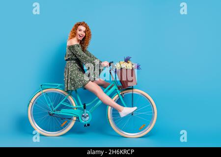 Full length profile photo of sweet lady ride bike wear dress sneakers isolated on blue color background Stock Photo