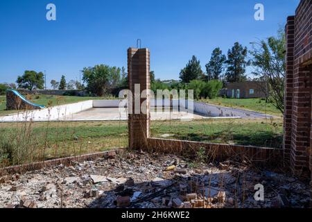 Abandoned swimming pool with a piece of broken down brick wall in front of it. Stock Photo