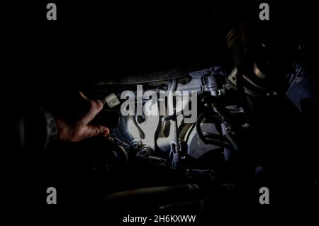 Shining a light into the open hood of vehicle to check the engine Stock Photo