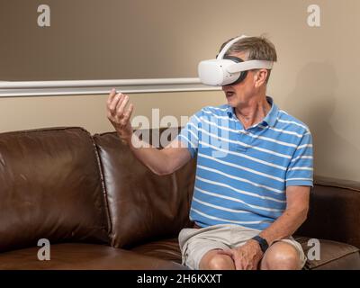Senior man reaching for object on a modern virtual reality VR headset in home Stock Photo