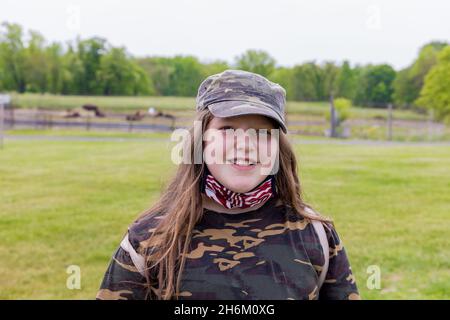 Girl with a smile wearing camouflage clothing and american flag mask. Military daughter. Stock Photo