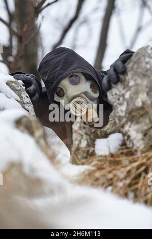 Gas mask man hiding in winter foresr Stock Photo