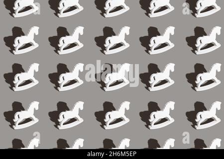 Christmas and New year concept. Seamless pattern made with wooden horse toys on light gray background. Flat lay. Stock Photo