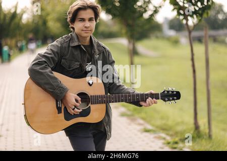 Concentrated teenage boy musician playing acoustic guitar outdoor. Handsome  boy love misuc Stock Photo - Alamy